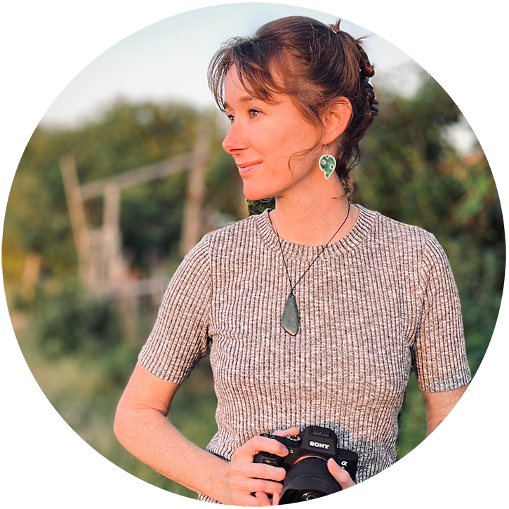 Portrait photo of Lu smiling, looking to the side, holding a camera