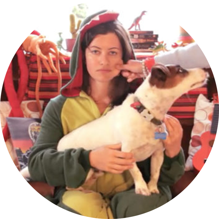 Char, team member of Matai Media, wearing a onesie with a dead pan expression while holding a dog.