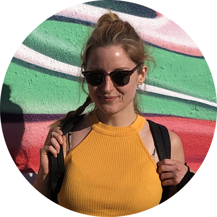 Lorna, team member of Matai Media, posing for a photo with a colorful street art wall background